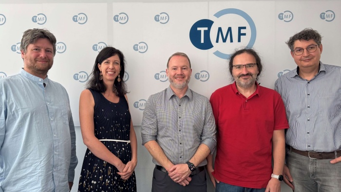 REDCap German User Group Fünf Personen, die vor einer Wand mit TMF-Logos stehen, lächeln in die Kamera.